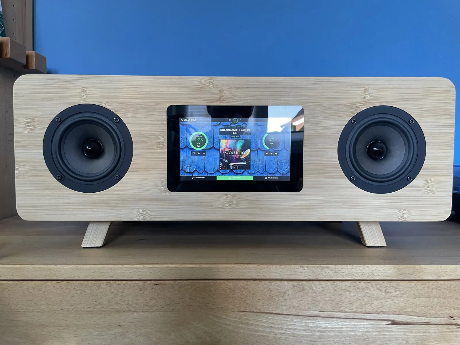 Diffusore stereo con frontale in bambù, due altoparlanti e un touchscreen al centro