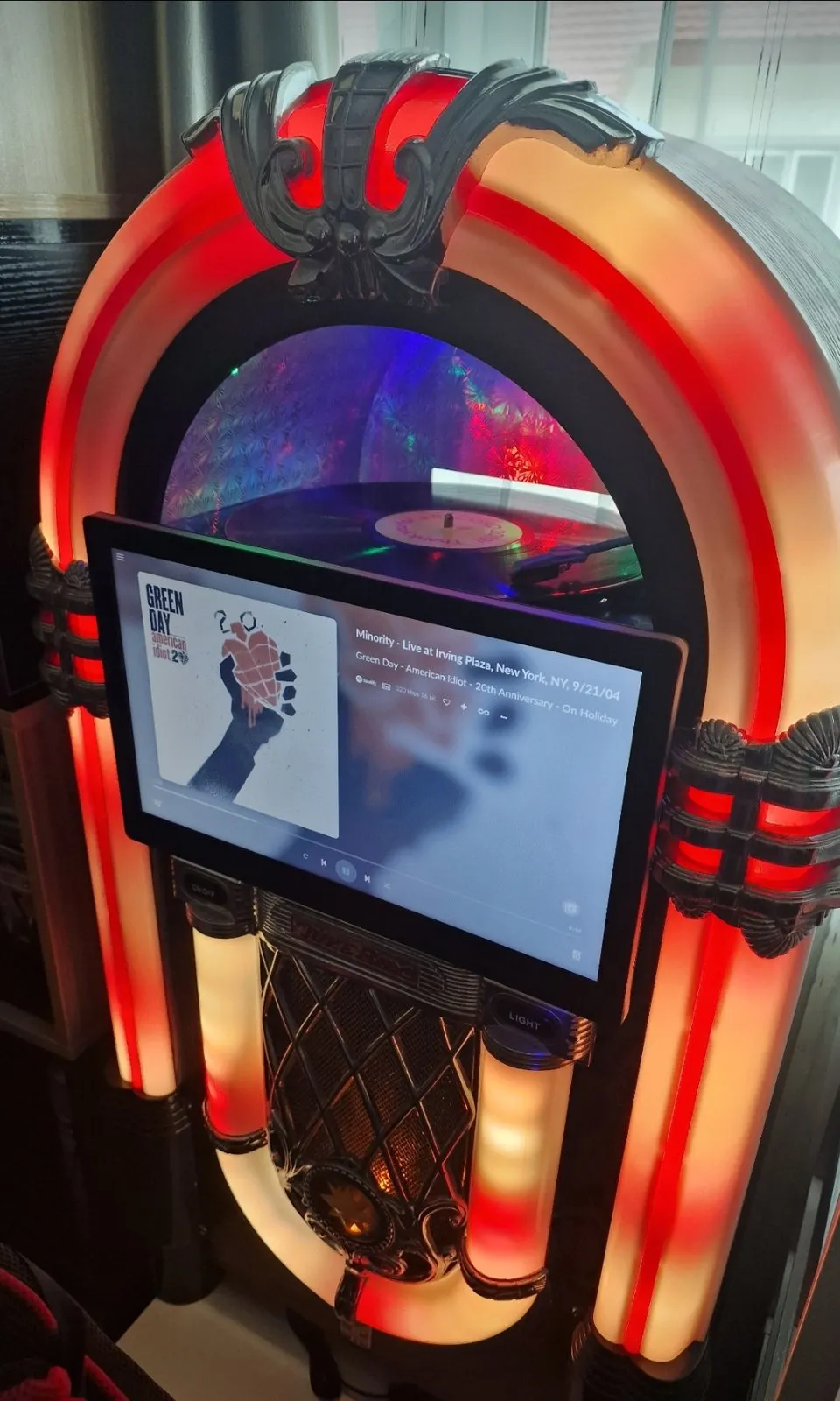 Jukebox illuminato di rosso e ambra, con un tablet che mostra la schermata In ascolto