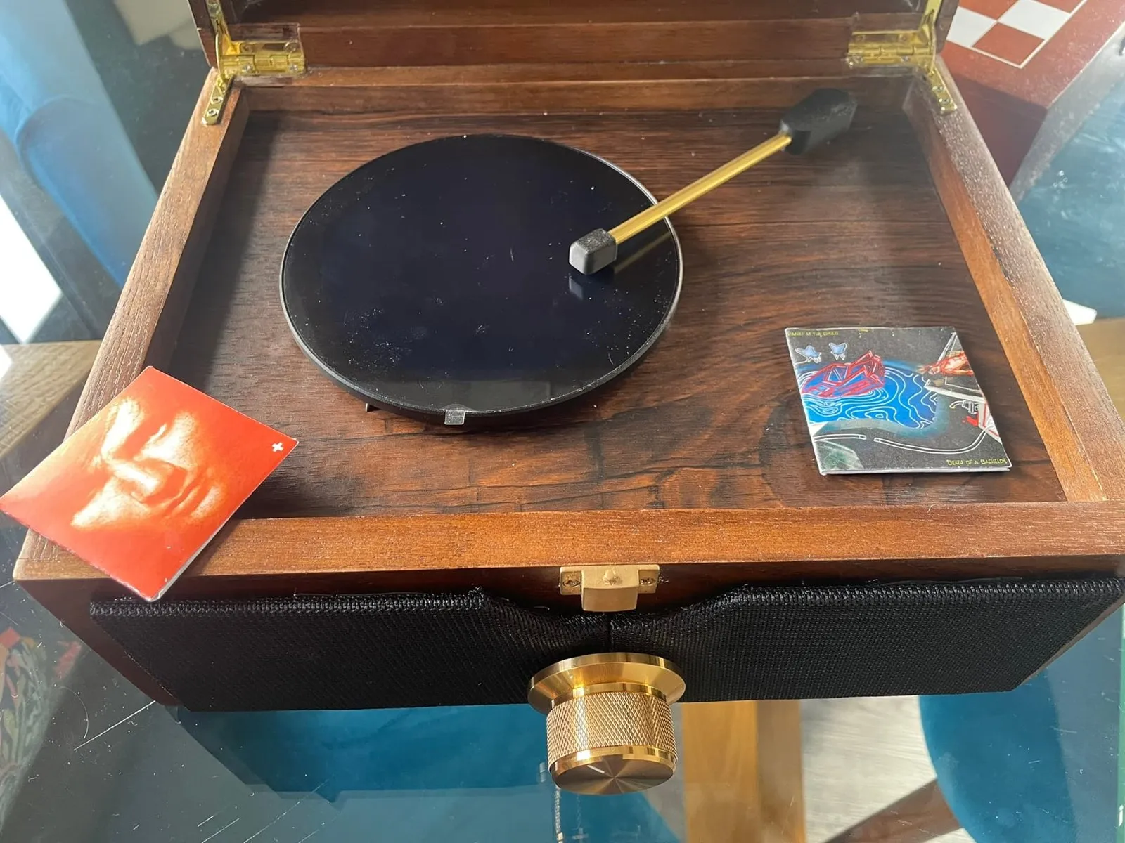 Scatola di legno aperta con uno schermo rotondo come un disco, un braccio e mini copertine di album