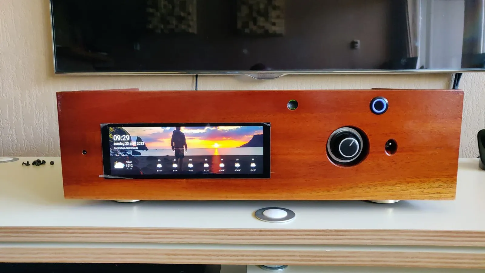 Streamer in legno con un ampio touchscreen e una manopola del volume, su un mobile TV